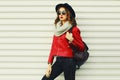 Portrait beautiful young woman with backpack posing wearing a red jacket, black round hat, scarf on white background