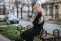 Portrait beautiful young woman on bench in urban background looking phone Royalty Free Stock Photo