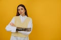 Portrait of a beautiful young woman with a bionic prosthetic arm in a white shirt on a yellow background.