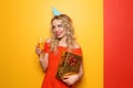 Portrait of beautiful young woman with birthday gift and glass of champagne on color background Royalty Free Stock Photo