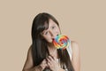 Portrait of beautiful young woman biting lollipop over colored background Royalty Free Stock Photo