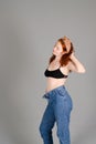 Portrait of beautiful young woman in black sports top and jeans with red curly hair, freckles and blue eyes Royalty Free Stock Photo