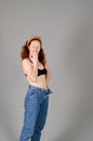 Portrait of beautiful young woman in black sports top and jeans with red curly hair, freckles and blue eyes Royalty Free Stock Photo