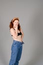 Portrait of beautiful young woman in black sports top and jeans with red curly hair, freckles and blue eyes Royalty Free Stock Photo