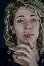 Portrait of a beautiful young woman with blond curly hair who with a finger on her chin looks indecisive or doubtful