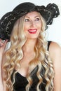 Portrait. Beautiful young woman blonde in a black dress and a hat with a neckline, beautifully smiling, red lipstick. Royalty Free Stock Photo
