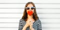 Portrait of beautiful young woman blowing her lips with lipstick with red sweet heart shaped lollipop on white background Royalty Free Stock Photo