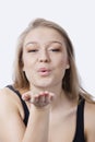 Portrait of beautiful young woman blowing kiss against white background Royalty Free Stock Photo