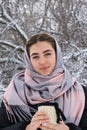 Portrait of beautiful young woman with blue eyes. Winter walk in snowy forest. Mug with hot drink in hand Royalty Free Stock Photo