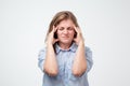 Portrait of beautiful young woman in blue shirt touching her temples feeling stress Royalty Free Stock Photo