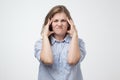 Portrait of beautiful young woman in blue shirt touching her temples feeling stress Royalty Free Stock Photo