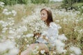 Beautiful young woman with a bouquet of white wild flowers sitting in the middle of grass in a meadow Royalty Free Stock Photo