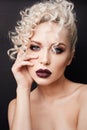 Portrait of a beautiful young woman with bright makeup and curly blond hair. Fashionable model girl with dark full lips Royalty Free Stock Photo