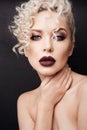 Portrait of a beautiful young woman with bright makeup and curly blond hair. Fashionable model girl with dark full lips Royalty Free Stock Photo