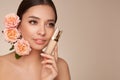 Beautiful young woman with foundation bottle and rose flowers Royalty Free Stock Photo