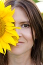 Portrait of a beautiful young woman. The woman covered the floor of her face with a sunflower flower. Woman portrait in a Royalty Free Stock Photo