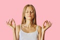 Young woman with closed eyes and hands in lotus gesture. Meditation, balance and peace of mind concept. Isolated over pink Royalty Free Stock Photo