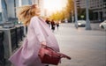 Portrait of a beautiful young woman in a coat with a charming smile whirling on the street in a big city Royalty Free Stock Photo