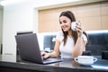 Portrait of a beautiful young woman with coffee cup using laptop in the kitchen at home Royalty Free Stock Photo