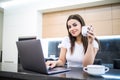 Portrait of a beautiful young woman with coffee cup using laptop in the kitchen at home Royalty Free Stock Photo