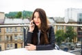 Portrait of beautiful young woman in coffee shop terrace, relaxing using smart phone, phone call conversation outdoors. Fashion fe Royalty Free Stock Photo