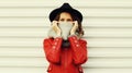 Portrait beautiful young woman covering her face with scarf wearing a red jacket, black round hat on white background Royalty Free Stock Photo