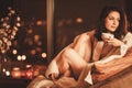 Portrait of beautiful young woman with cup of hot drink in cozy home interior Royalty Free Stock Photo