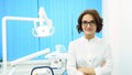Portrait of beautiful young woman dentist standing arms crossed in the dental clinic cabinet. Confident doctor in Royalty Free Stock Photo