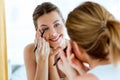 Beautiful young woman doing make-up near mirror at home. Royalty Free Stock Photo