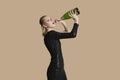 Portrait of beautiful young woman drinking champagne from bottle over colored background Royalty Free Stock Photo