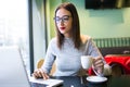 Beautiful young woman drinking coffee while using her laptop in the coffee shop. Royalty Free Stock Photo