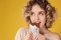 Portrait of beautiful young woman eating chocolate on color background Royalty Free Stock Photo