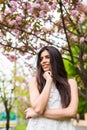 Portrait of beautiful young woman enjoying sunny day in park during cherry blossom season on a nice spring day Royalty Free Stock Photo