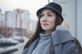 Portrait of an attractive young girl on the background of the city. A girl in a black hat and gray coat walks around the Royalty Free Stock Photo