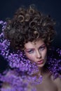 Portrait of beautiful young woman with fancy hairdo and violet flowers around her face, soft focus, grainy