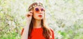 Portrait of beautiful young woman and flowers wearing floral headband, sunglasses on spring blooming garden background Royalty Free Stock Photo