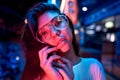 Portrait of a beautiful young woman with glasses in futuristic neon light