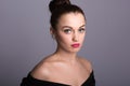 Portrait of a beautiful young woman on a gray background. Bare shoulders