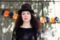 Portrait of beautiful young woman in Halloween costume. brown-haired woman in black guipure dress and black hat Royalty Free Stock Photo