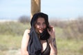 Portrait of a beautiful young woman with her hair covered with a black veil. The woman is in a swimming costume and leaning on a Royalty Free Stock Photo