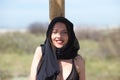 Portrait of a beautiful young woman with her hair covered with a black veil. The woman is in a swimming costume and leaning on a Royalty Free Stock Photo