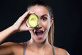 Beautiful young woman holding avocado over black background.