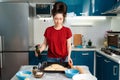 Portrait of a beautiful young woman holding a baking tray with pizza dough and a bottle of butter. The concept of home Royalty Free Stock Photo