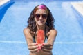 Portrait of a beautiful young woman holding a piece of watermelon and smiling. Blue Swimming pool water background. Summer and Royalty Free Stock Photo