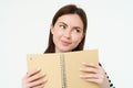 Portrait of beautiful young woman, holding daily planner, writing in her diary, making notes in notebook and smiling Royalty Free Stock Photo