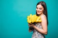 Perfect present. Portrait of a beautiful young woman in ssummer dress holding yellow tulips bouquet isolated over blue background Royalty Free Stock Photo