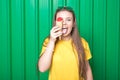 Portrait of beautiful young woman with ice cream against green wall.