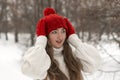 Portrait of beautiful young woman in knitted red hat and mittens and woolen sweater in winter park. Ladies knitwear Royalty Free Stock Photo