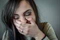 Portrait of a beautiful young woman with long brown hair covering her mouth as she bursts out laughing Royalty Free Stock Photo