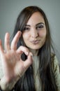 Portrait of a beautiful young woman with long brown hair gesturing ok with her hand while smiling Royalty Free Stock Photo